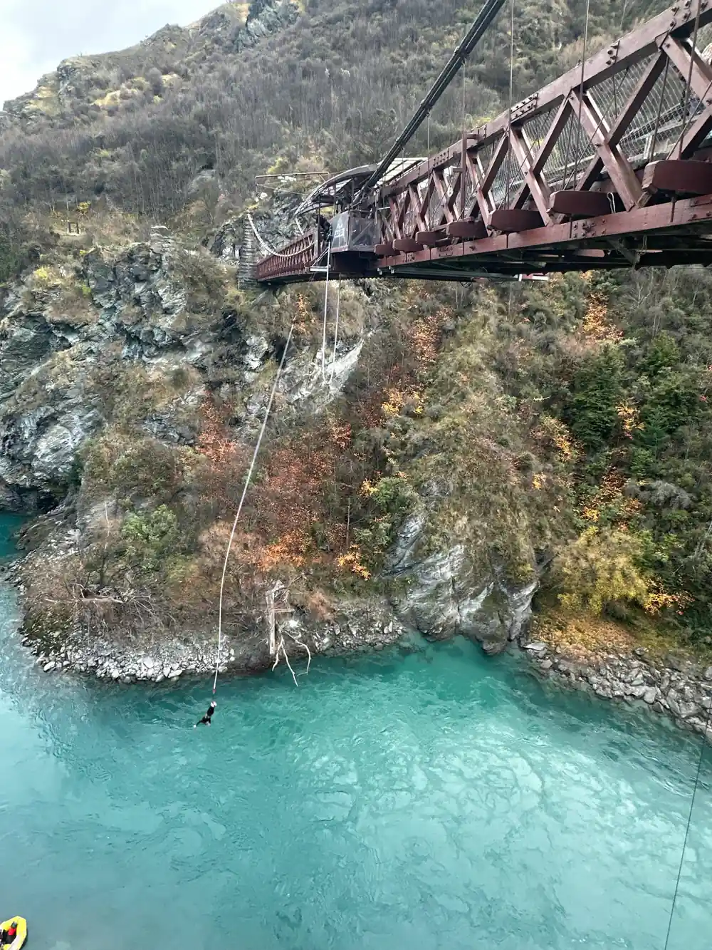The bridge in autumn colour with a cord dropping to the river