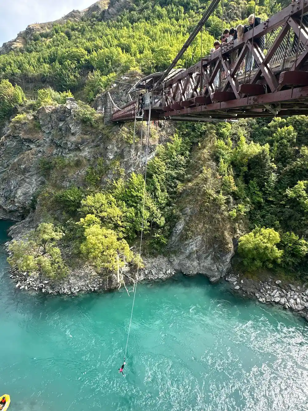 The bridge from downstream with a cord hanging to the river below