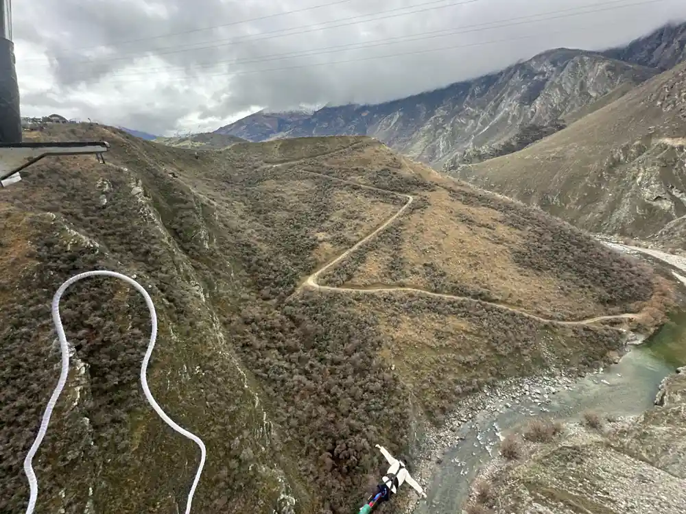A cableway crossing a dry canyon with a zigzag access road below