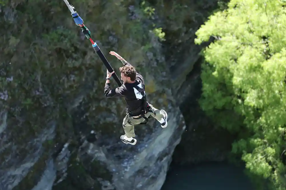 A jumper with arms wide falling past the rock into the gorge