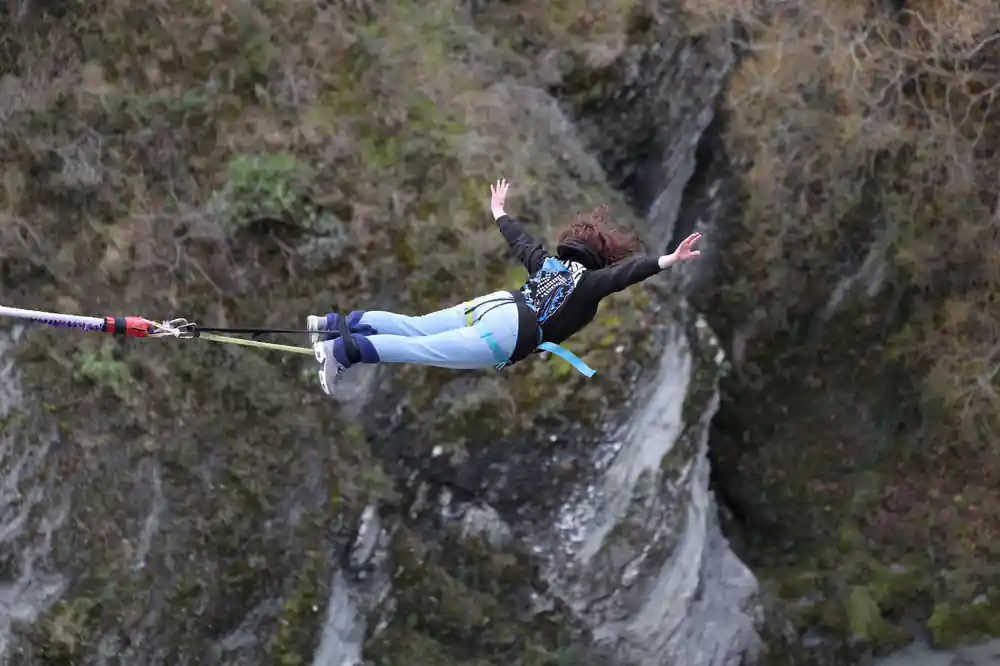 A jumper diving out horizontally with arms spread over the gorge