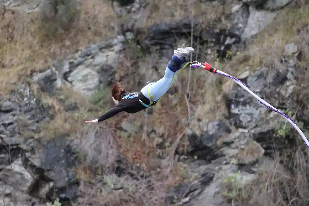 A jumper diving out from the platform with the cord trailing behind