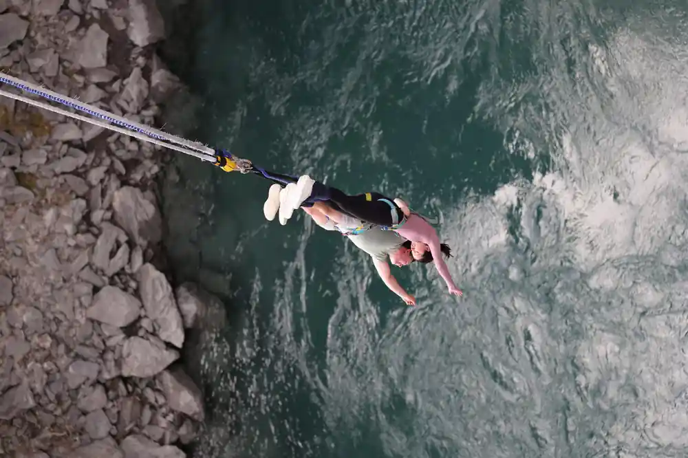 A jumper falling head first past the rock face beside the bridge