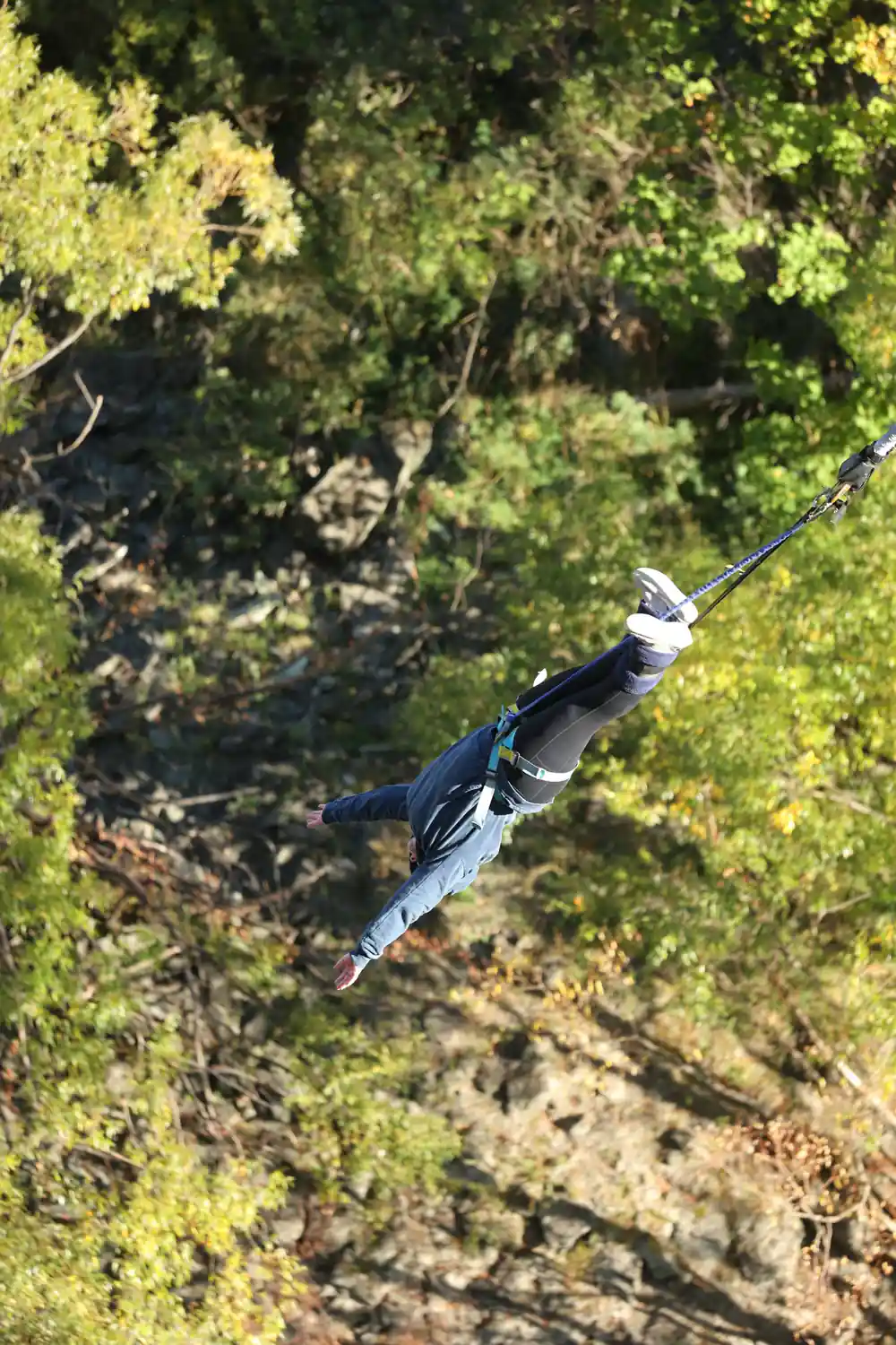 A jumper falling past the rock with the cord running up out of frame