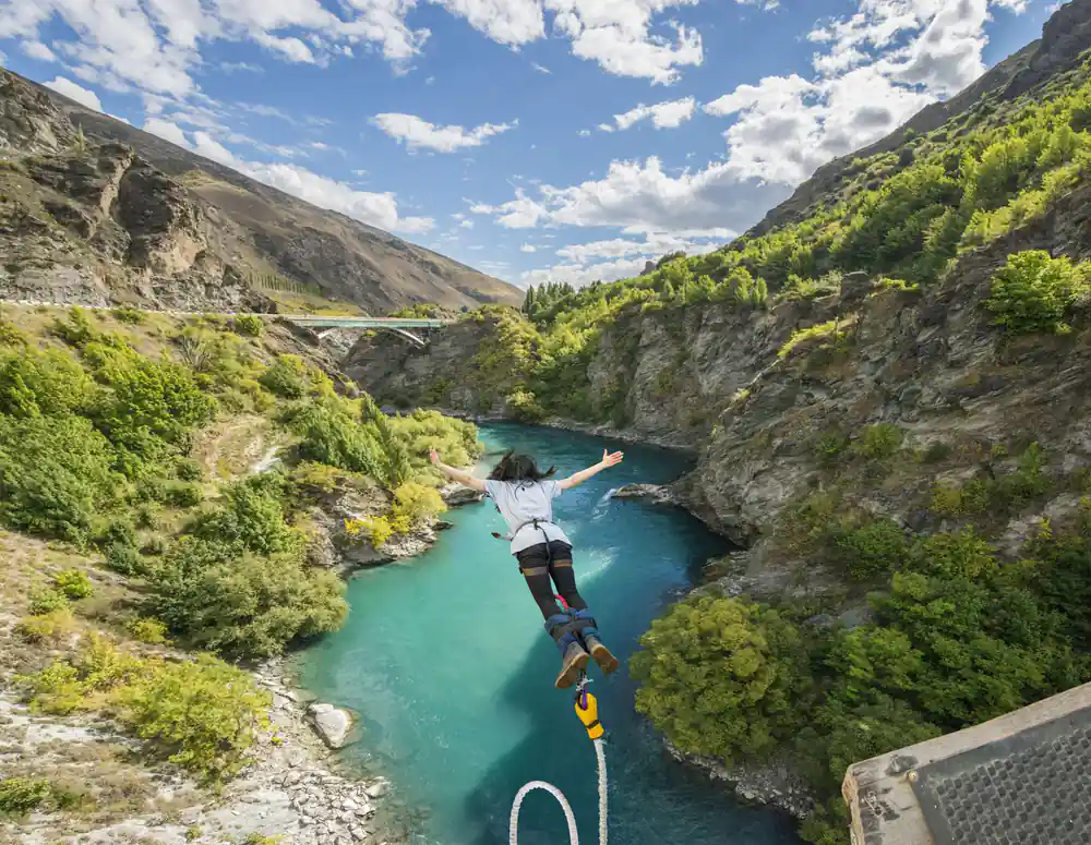 A jumper falling towards the turquoise river with the gorge open behind