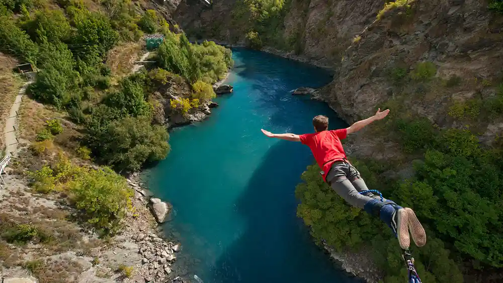 A jumper in free fall above the green river between rock walls