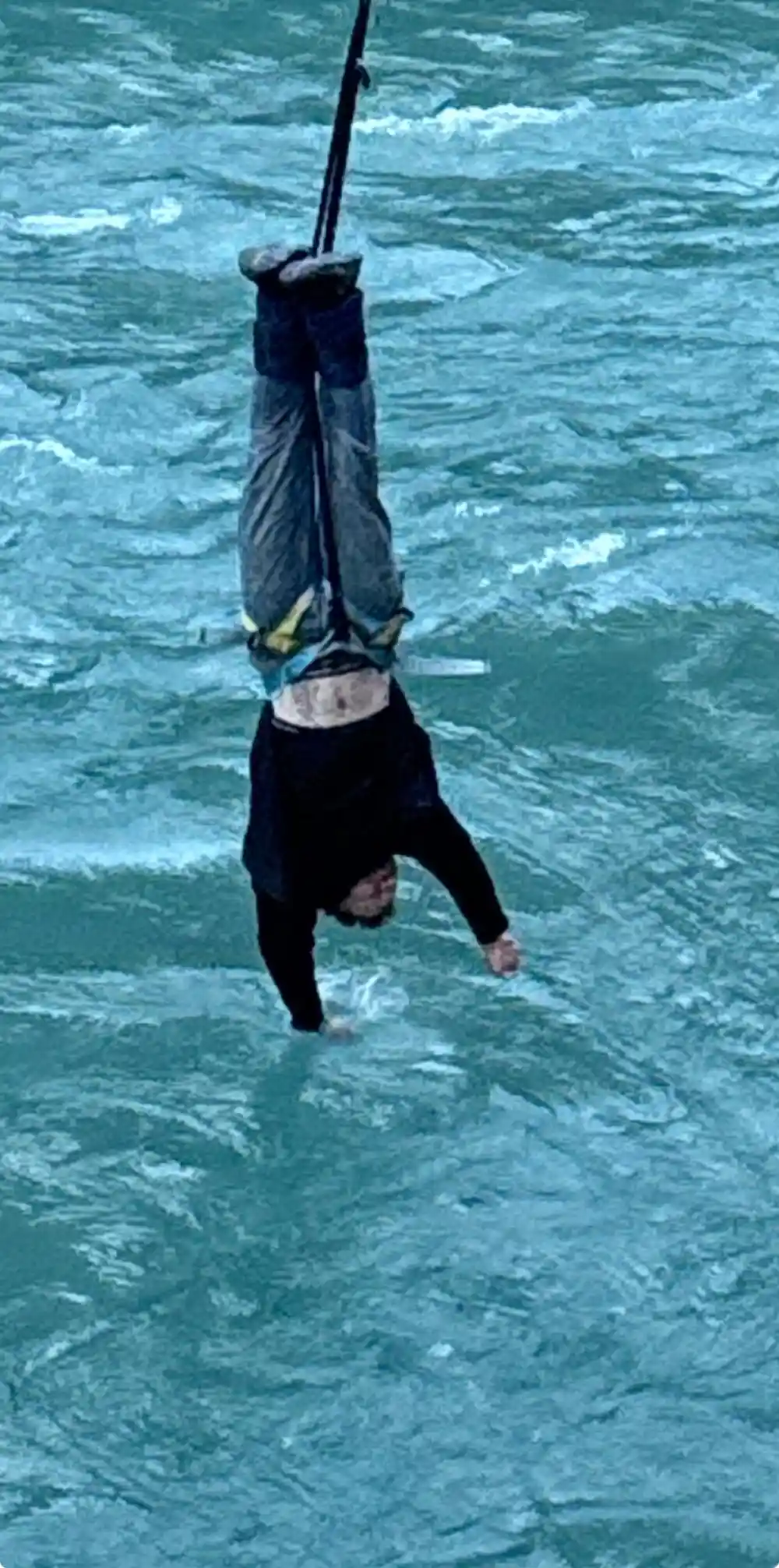 A jumper going into the river to the waist at the bottom of the arc