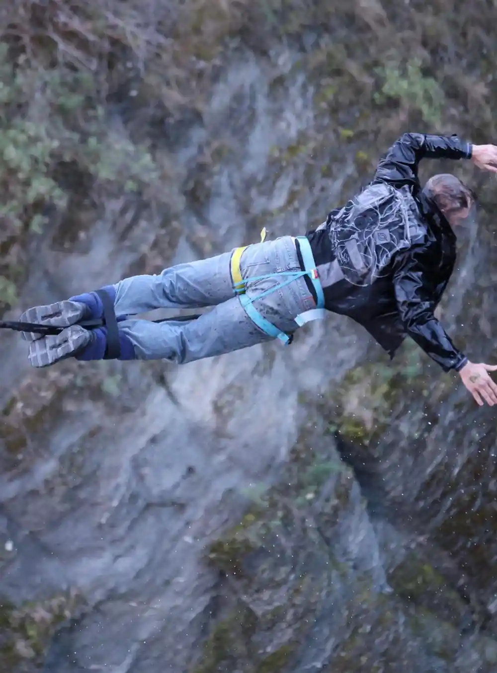 A jumper stretched horizontally against grey rock, arms out